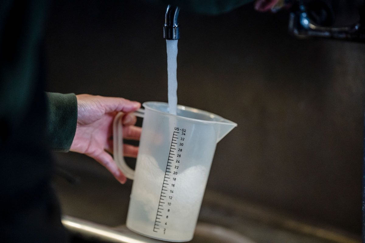 Hand holding a measuring jug under a running faucet